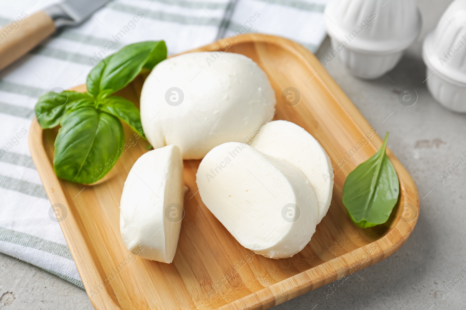 Pieces of delicious mozzarella cheese and basil leaves on grey textured table, closeup Photo of Pieces of delicious mozzarella cheese and basil leaves on grey textured table, closeup