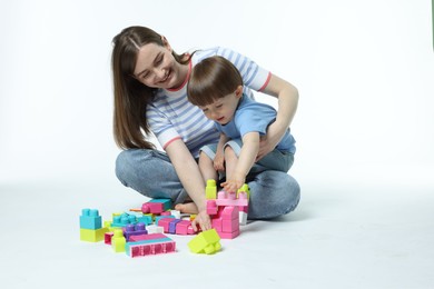 Photo of Mother and son playing with building bricks on white background