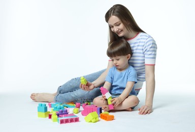 Photo of Mother and son playing with building bricks on white background