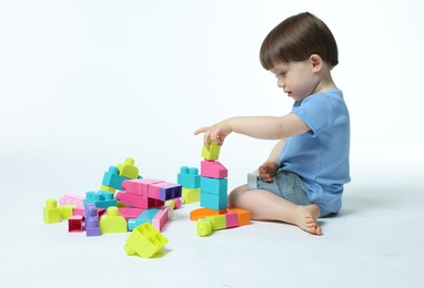 Photo of Cute little boy playing with building bricks on white background