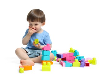 Photo of Cute little boy playing with building bricks on white background