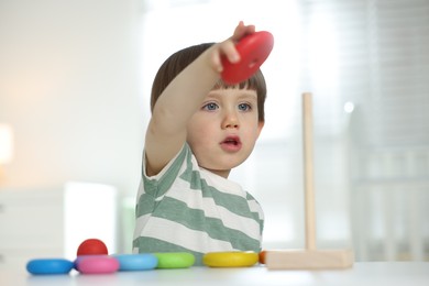 Photo of Cute little child playing with toy pyramid at table indoors