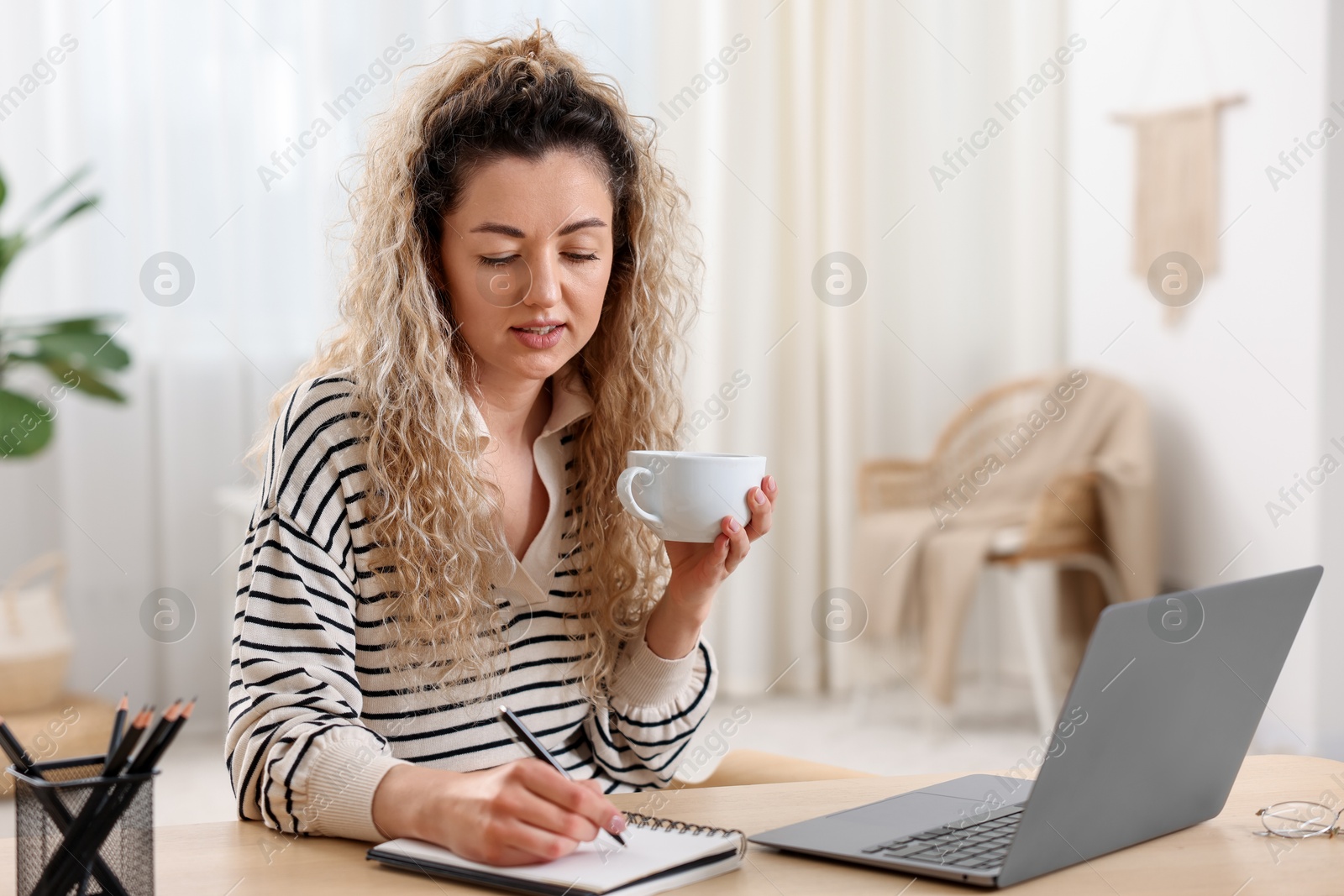Photo of Woman working with laptop at desk in home office