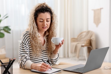 Photo of Woman working with laptop at desk in home office
