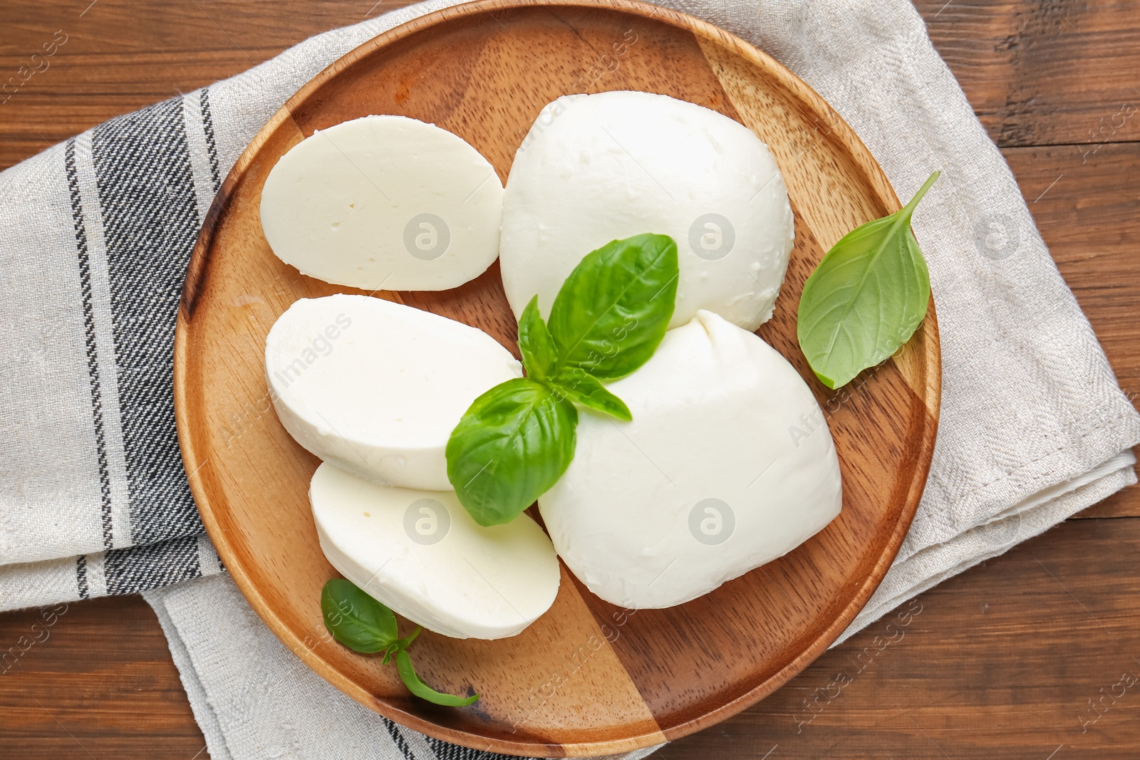 Pieces of delicious mozzarella cheese and basil leaves on wooden table, top view Photo of Pieces of delicious mozzarella cheese and basil leaves on wooden table, top view