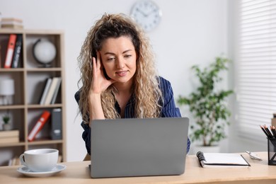 Photo of Woman working with laptop at desk in home office