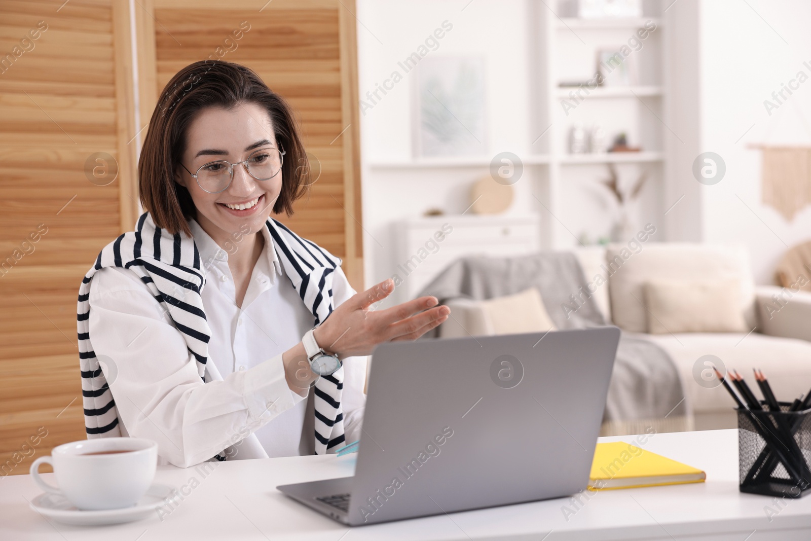Smiling woman having videochat by laptop at desk in home office Photo of Smiling woman having videochat by laptop at desk in home office