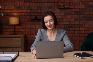Photo of Smiling woman working with laptop at desk in home office