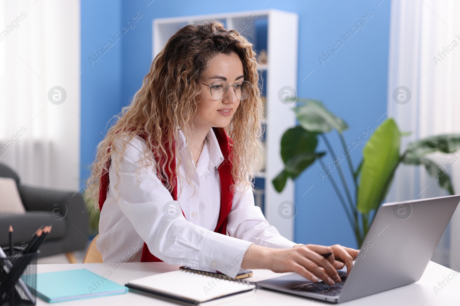 Woman working with laptop at desk in home office Photo of Woman working with laptop at desk in home office