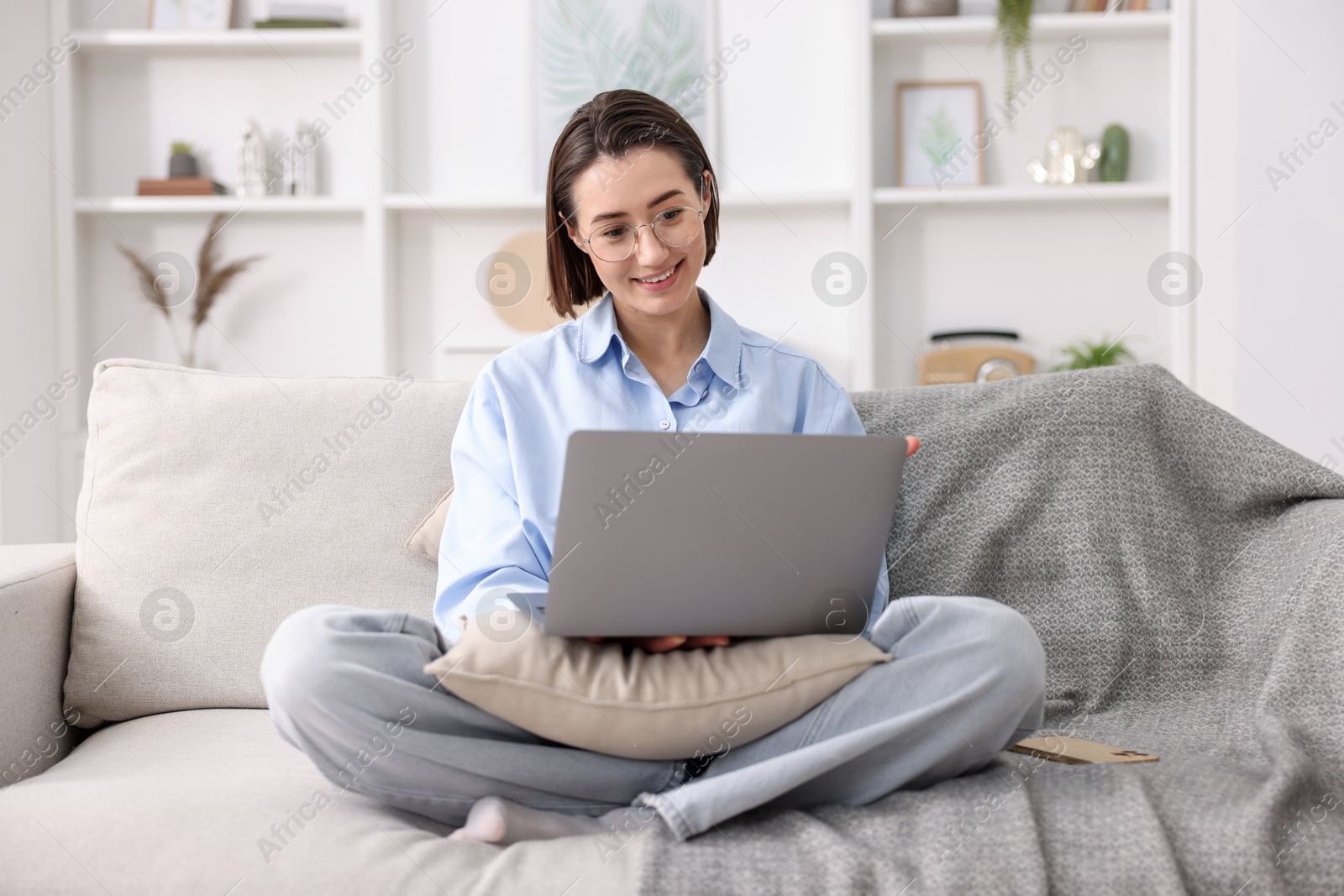 Smiling woman working with laptop on sofa in home office Photo of Smiling woman working with laptop on sofa in home office