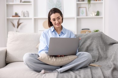 Photo of Smiling woman working with laptop on sofa in home office