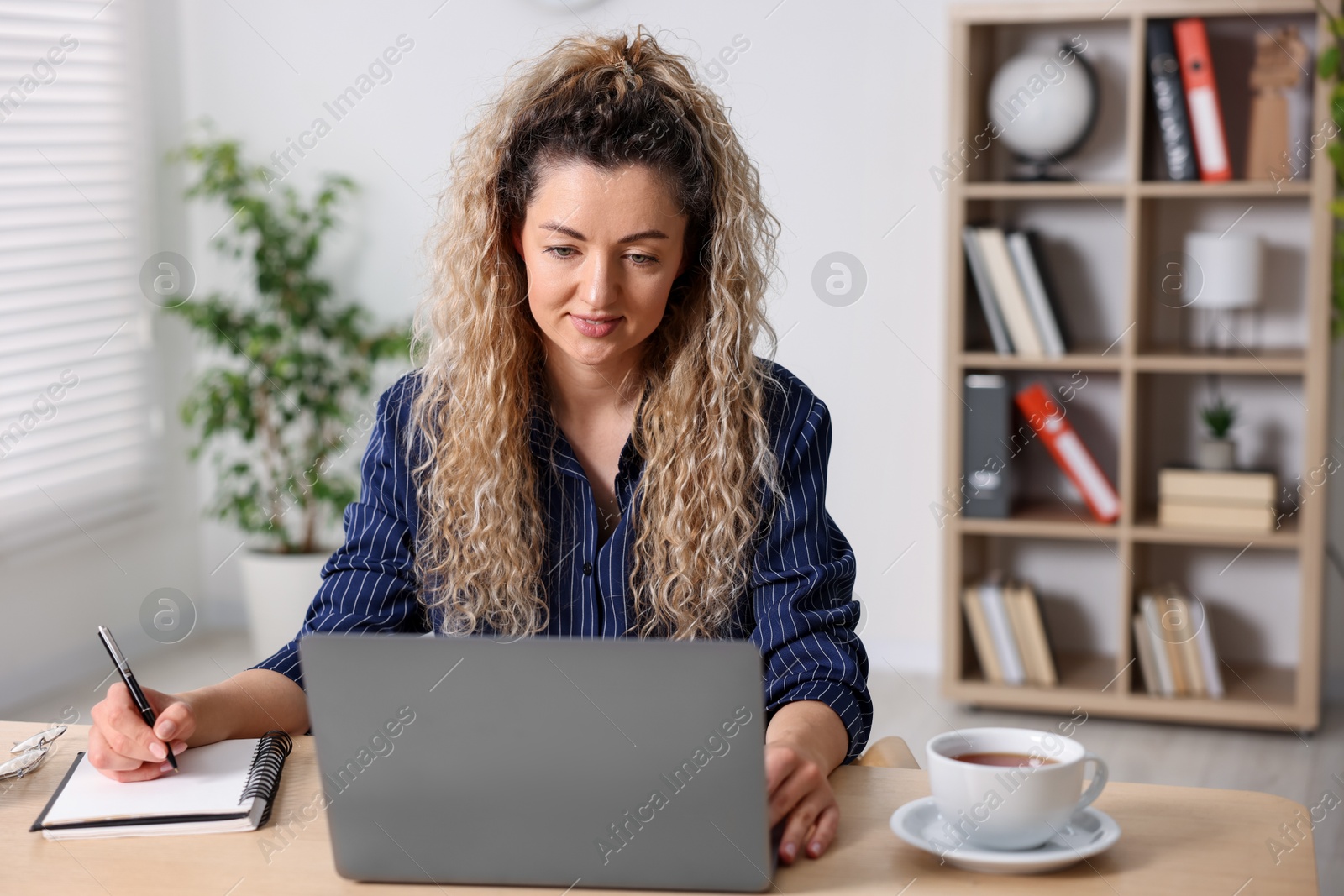 Photo of Woman working with laptop at desk in home office