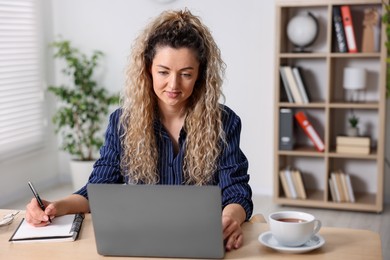 Photo of Woman working with laptop at desk in home office