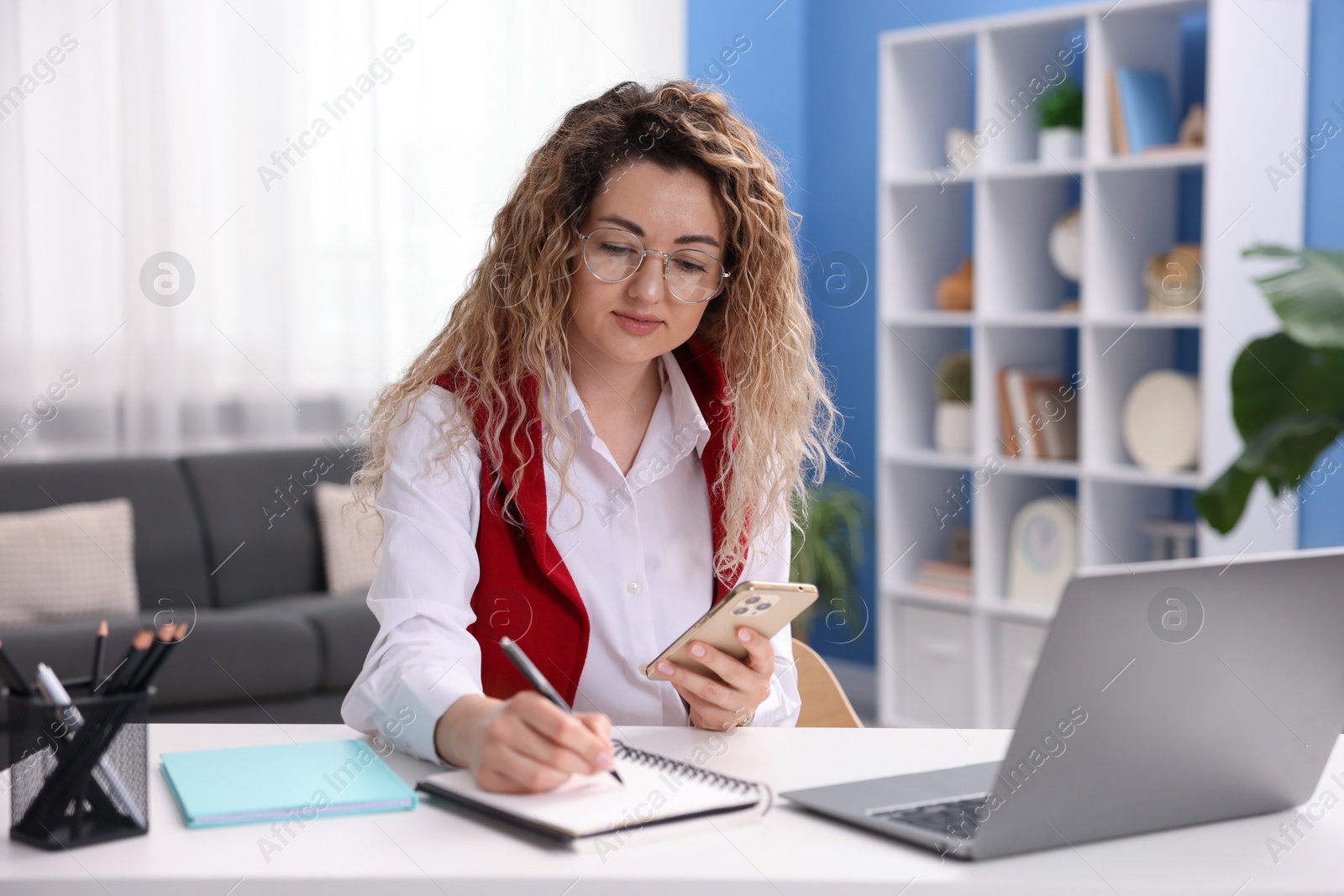 Photo of Woman with smartphone working at desk in home office