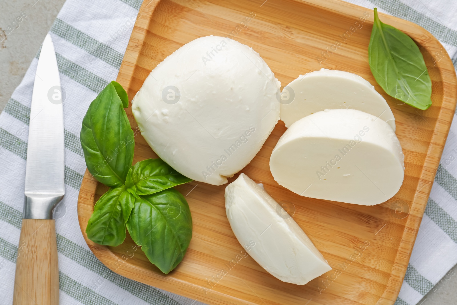 Pieces of delicious mozzarella cheese, basil leaves and knife on grey table, top view Photo of Pieces of delicious mozzarella cheese, basil leaves and knife on grey table, top view
