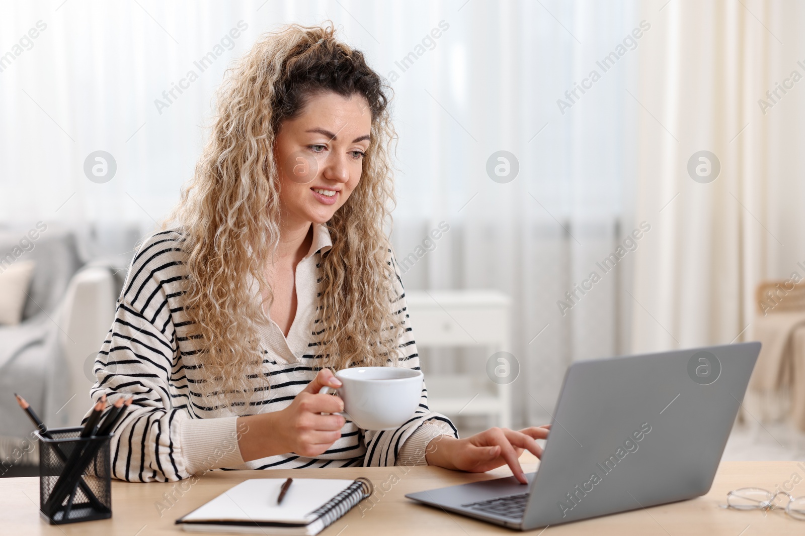 Photo of Smiling woman working with laptop at desk in home office