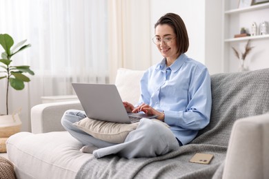 Photo of Smiling working with laptop on sofa in home office