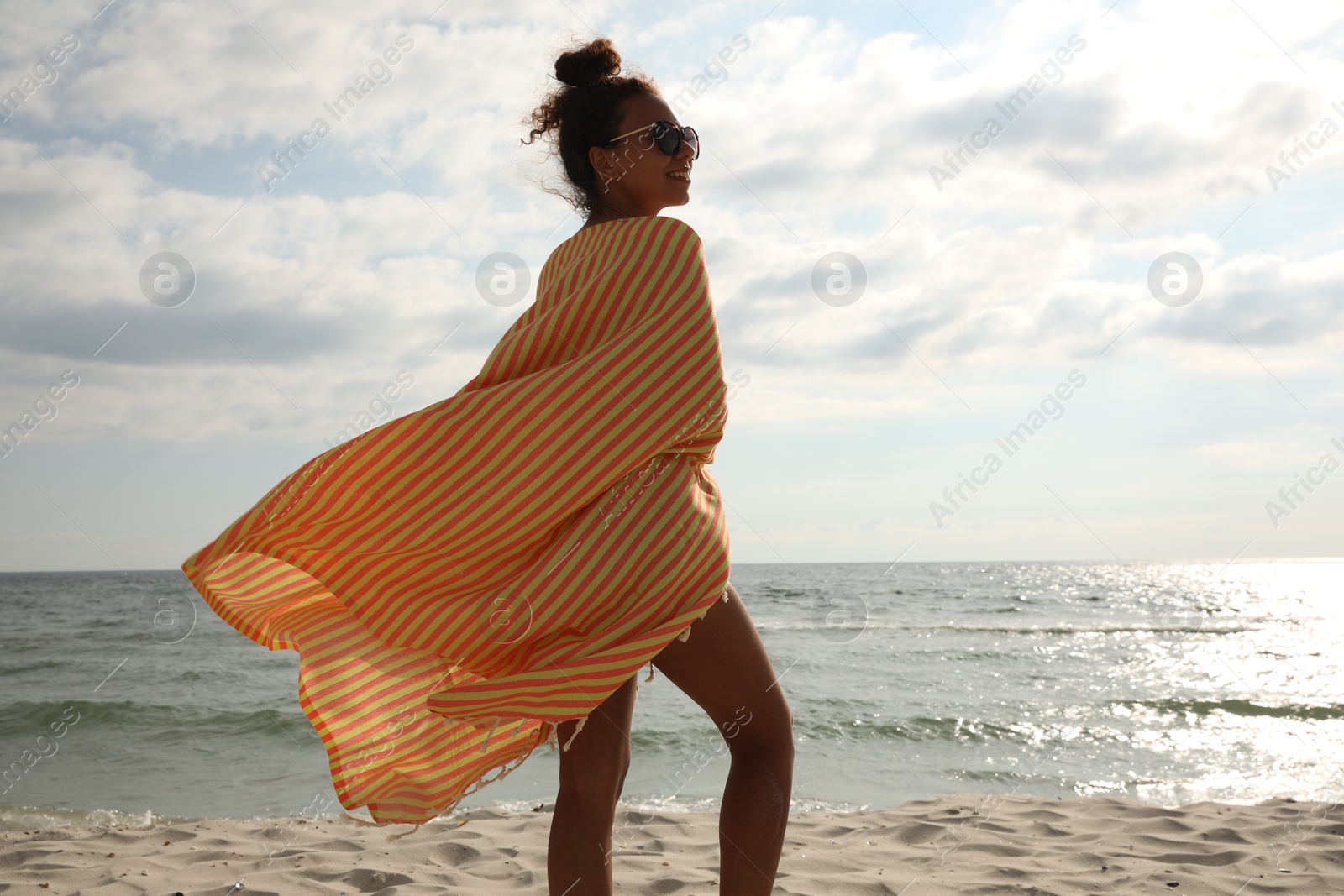 Beautiful African American woman with beach towel on seashore Photo of Beautiful African American woman with beach towel on seashore