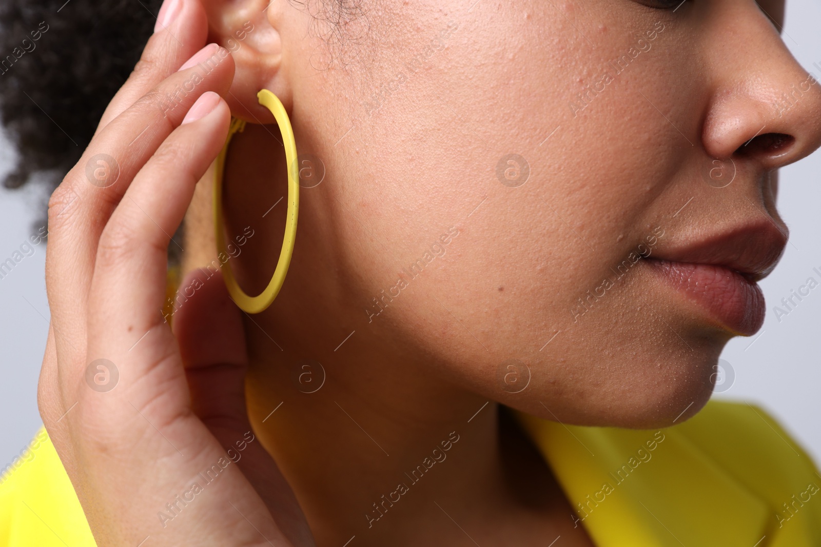 Young woman wearing elegant yellow earring on light grey background, closeup Photo of Young woman wearing elegant yellow earring on light grey background, closeup