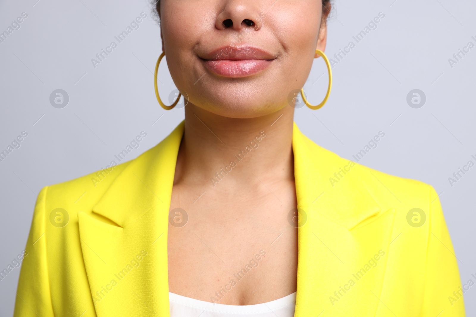 Young woman wearing elegant yellow earrings on light grey background, closeup Photo of Young woman wearing elegant yellow earrings on light grey background, closeup