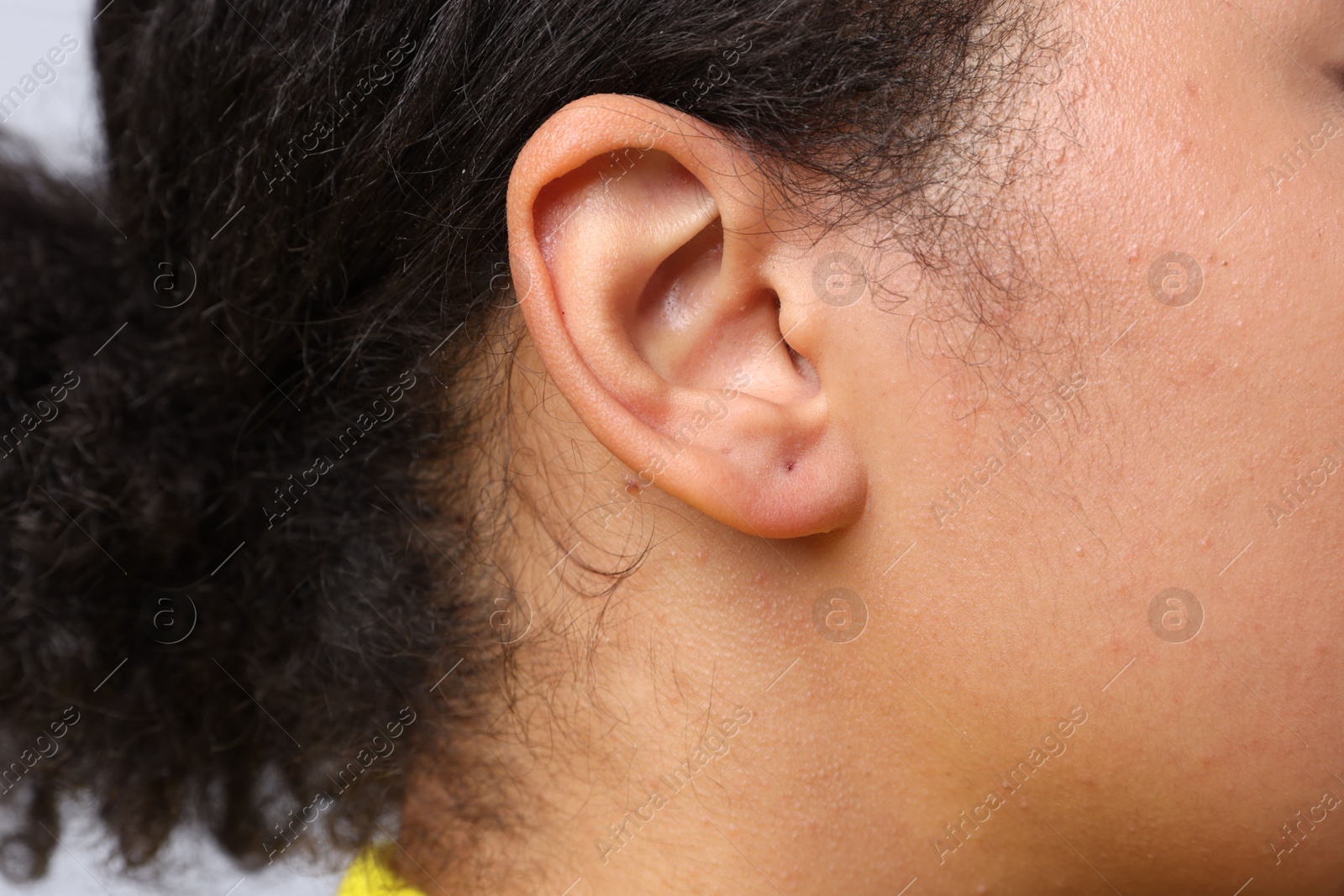 Young woman with pierced ear on light grey background, closeup Photo of Young woman with pierced ear on light grey background, closeup