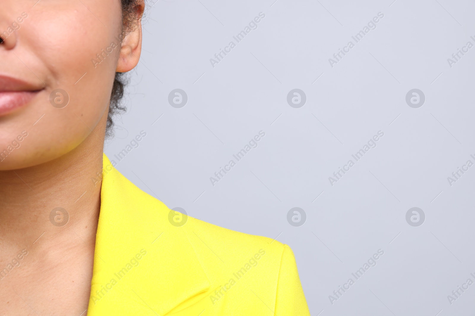 Young woman with pierced ear on light grey background, closeup. Space for text Photo of Young woman with pierced ear on light grey background, closeup. Space for text