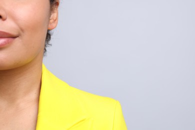 Photo of Young woman with pierced ear on light grey background, closeup. Space for text