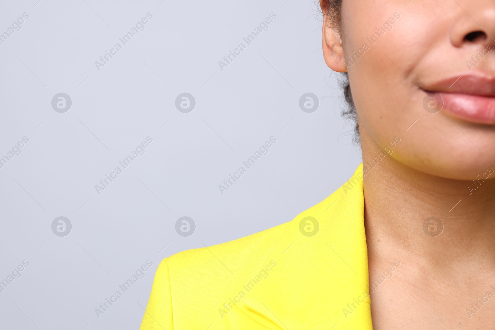 Young woman with pierced ear on light grey background, closeup. Space for text Photo of Young woman with pierced ear on light grey background, closeup. Space for text