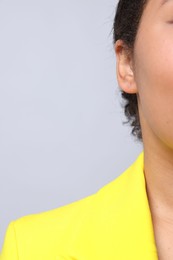 Photo of Young woman with pierced ear on light grey background, closeup. Space for text