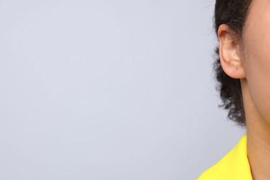 Photo of Young woman with pierced ear on light grey background, closeup. Space for text
