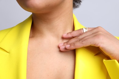 Photo of Young woman wearing elegant ring on light grey background, closeup