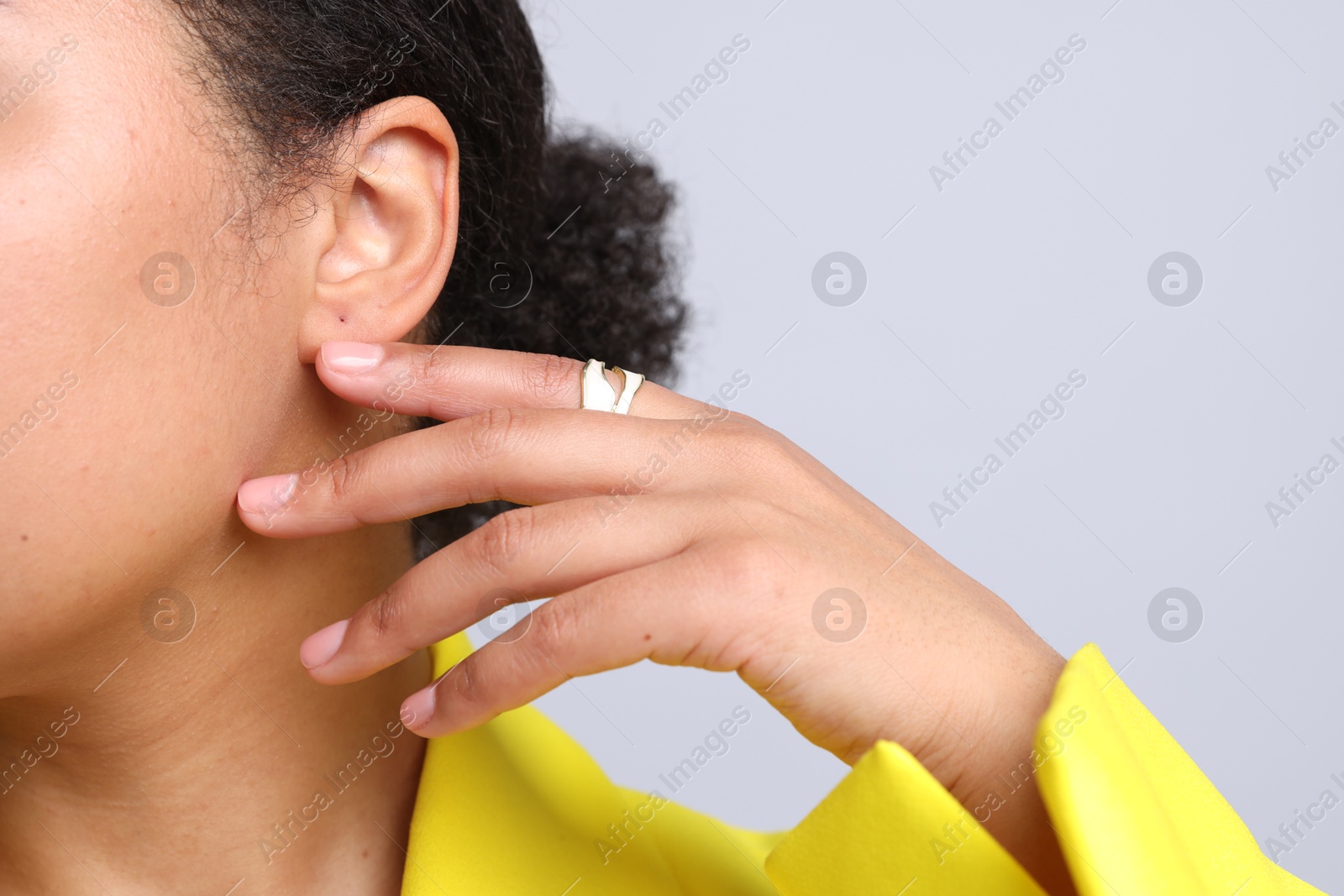 Young woman wearing elegant ring on light grey background, closeup. Space for text Photo of Young woman wearing elegant ring on light grey background, closeup. Space for text