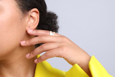 Photo of Young woman wearing elegant ring on light grey background, closeup. Space for text