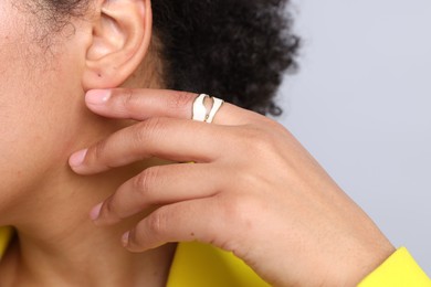 Photo of Young woman wearing elegant ring on light grey background, closeup