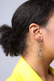 Photo of Young woman wearing elegant silver earring on light grey background, closeup