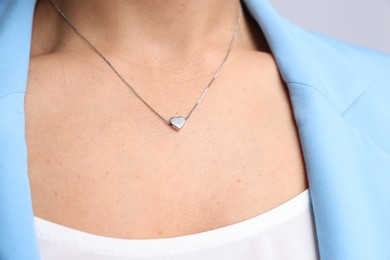 Photo of Young woman wearing elegant silver necklace on light grey background, closeup