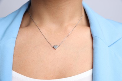 Photo of Young woman wearing elegant silver necklace on light grey background, closeup