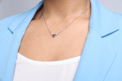 Photo of Young woman wearing elegant silver necklace on light grey background, closeup