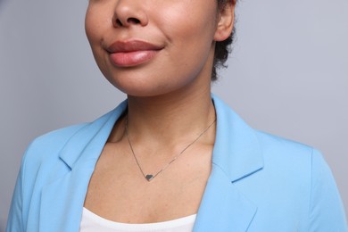 Photo of Young woman wearing elegant silver necklace on light grey background, closeup