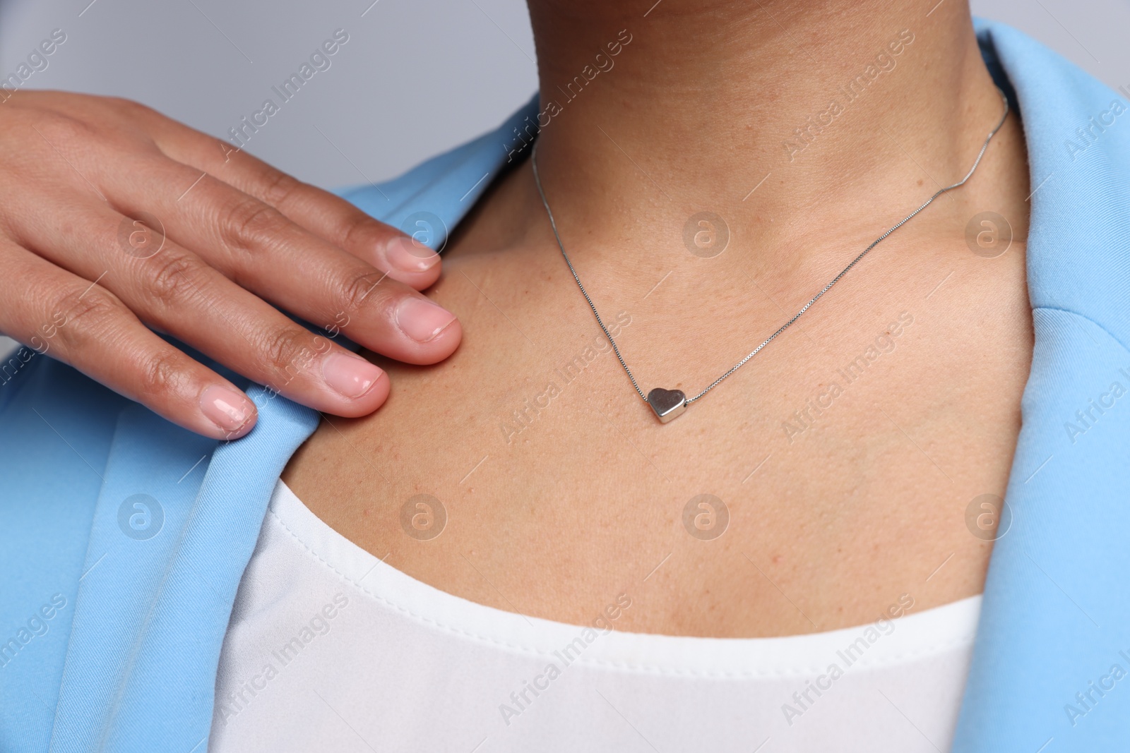 Photo of Young woman wearing elegant silver necklace on light grey background, closeup