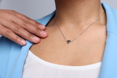 Photo of Young woman wearing elegant silver necklace on light grey background, closeup