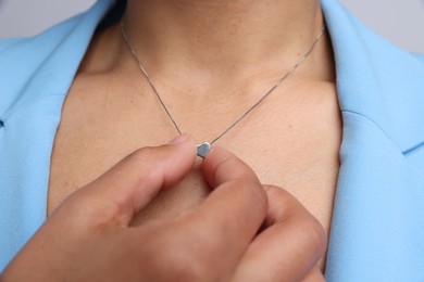 Photo of Young woman wearing elegant silver necklace on light grey background, closeup