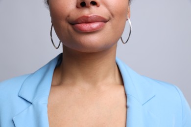Photo of Young woman wearing elegant silver earrings on light grey background, closeup
