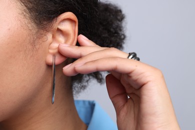 Photo of Young woman wearing elegant silver earring and ring on light grey background, closeup