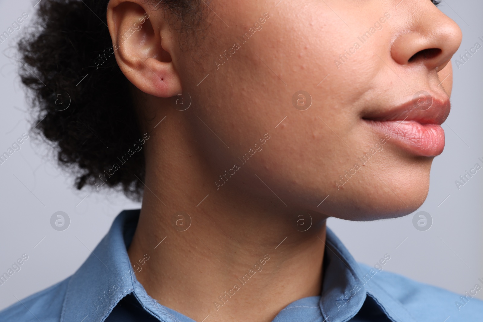 Young woman with pierced ear on light grey background, closeup Photo of Young woman with pierced ear on light grey background, closeup