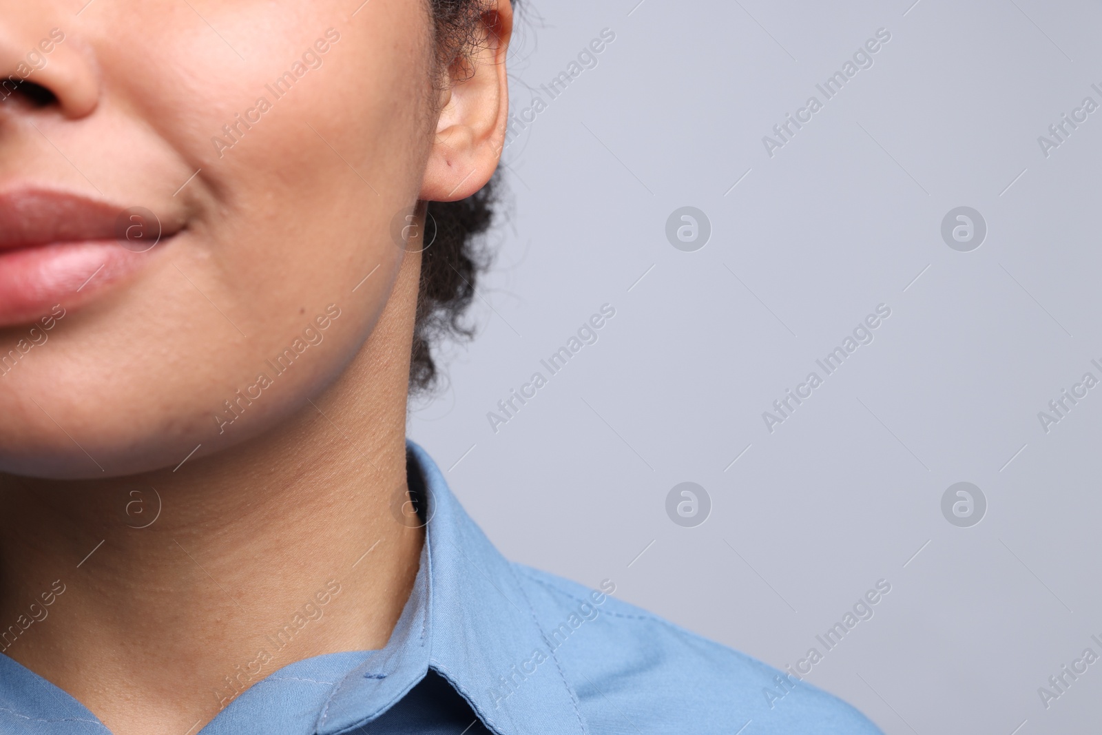 Young woman with pierced ear on light grey background, closeup. Space for text Photo of Young woman with pierced ear on light grey background, closeup. Space for text