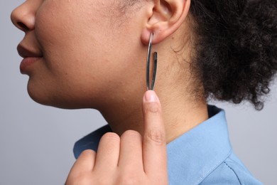 Photo of Young woman wearing elegant silver earring on light grey background, closeup