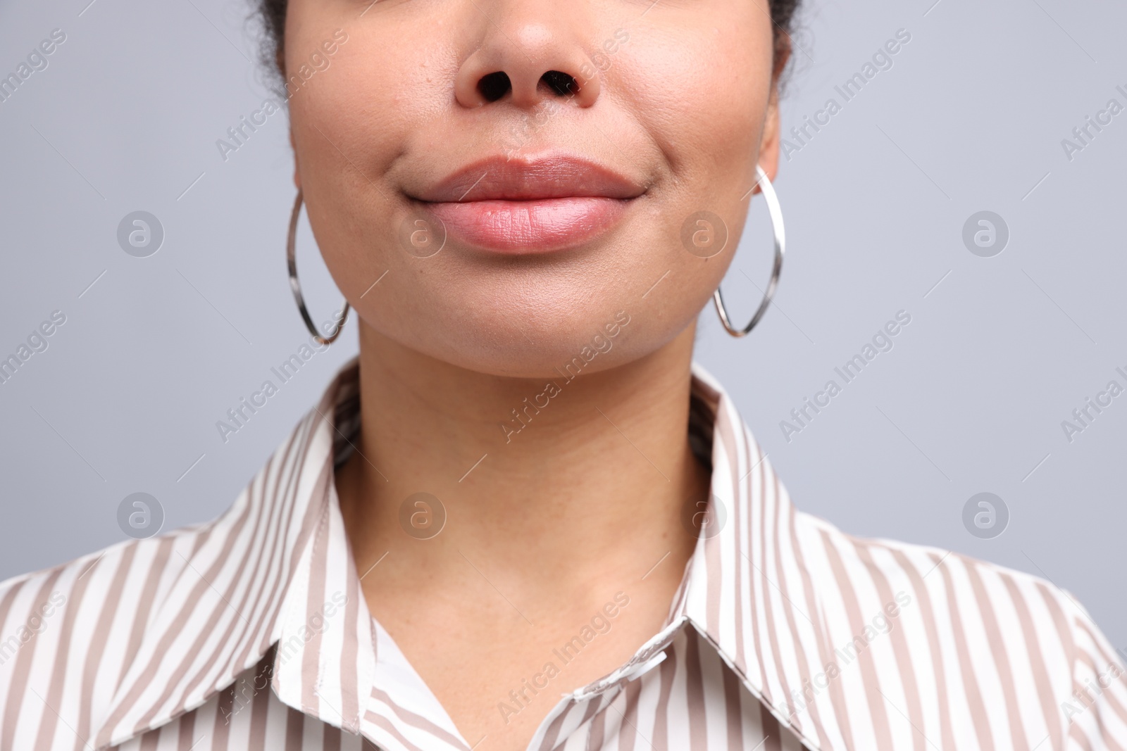 Photo of Young woman wearing elegant silver earrings on light grey background, closeup