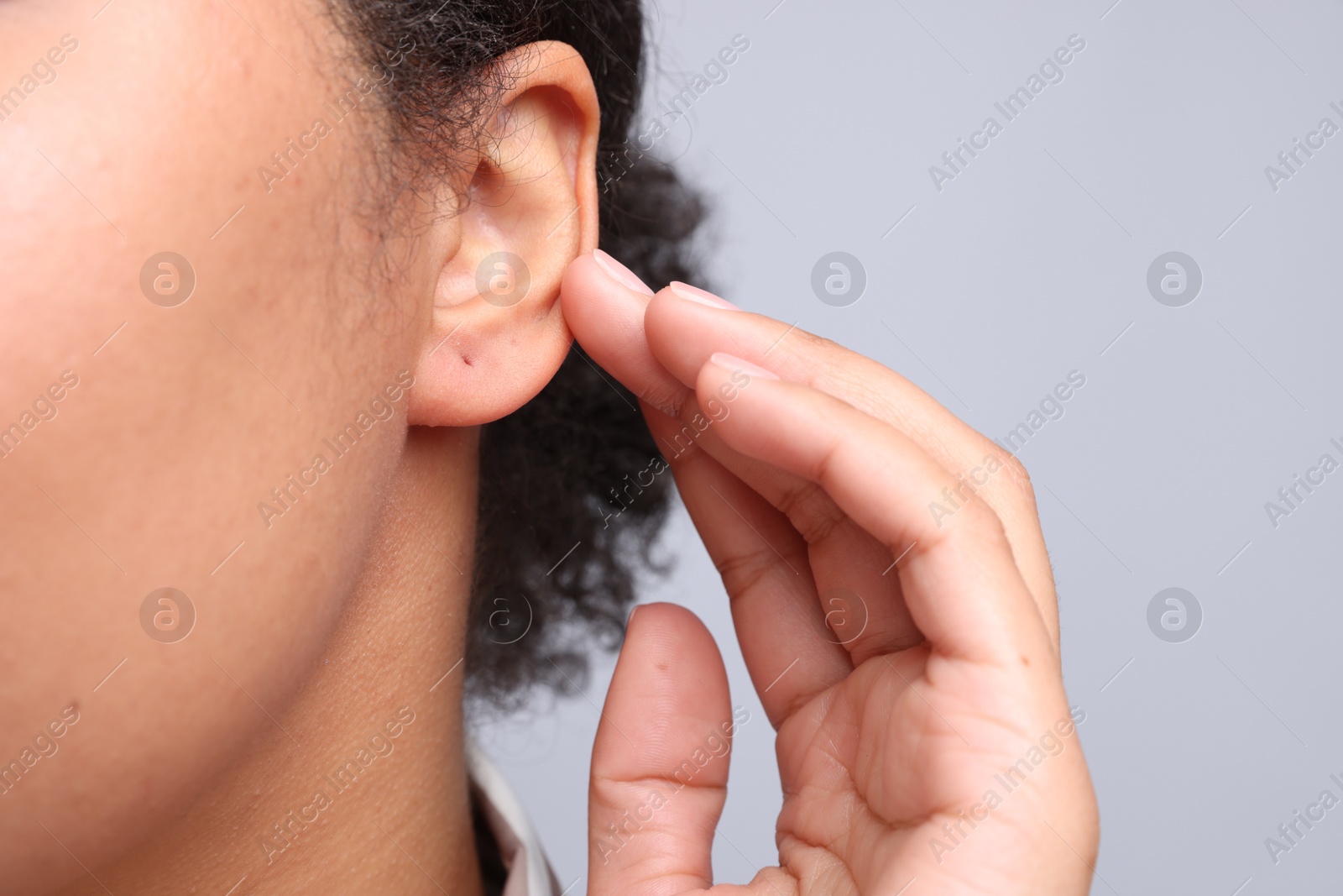 Young woman with pierced ear on light grey background, closeup Photo of Young woman with pierced ear on light grey background, closeup