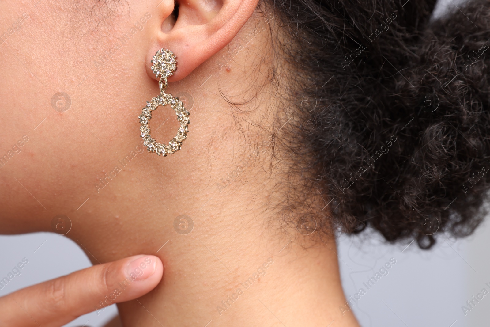 Photo of Young woman wearing elegant earring on light grey background, closeup